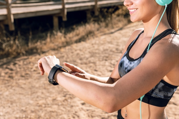 Sportliche Frau des mittleren Schusses, die ihre Smartwatch überprüft