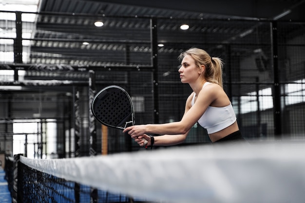 Kostenloses Foto sportliche frau des mittleren schusses, die paddle-tennis spielt