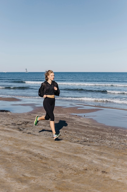 Sportliche Frau, die am Strand läuft