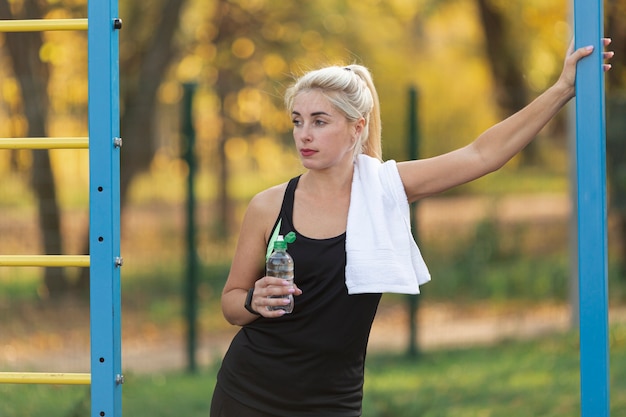 Sportliche Frau, die eine Flasche Wasser anhält