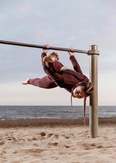 Sportliche Frau, die Fitnessübungen im Freien am Strand tut