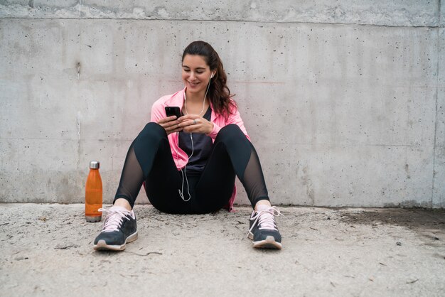 Sportliche Frau, die ihr Telefon benutzt.