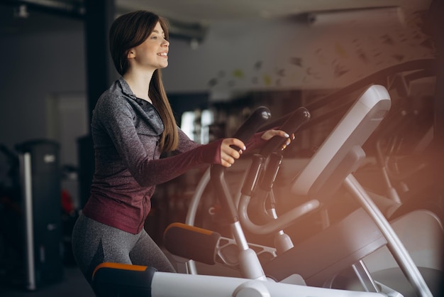 Sportliche Frau, die im Fitnessstudio auf Orbitrek radelt