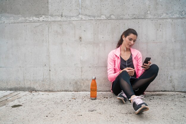 Sportliche Frau, die sein Telefon benutzt