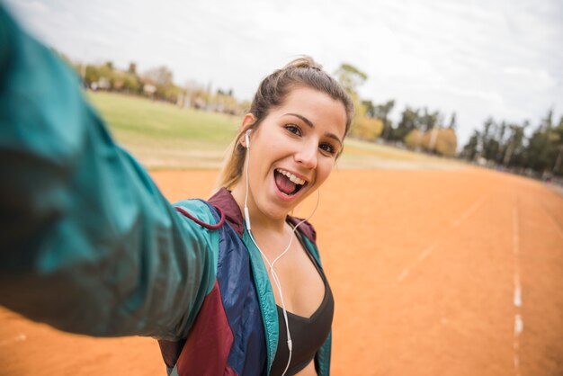 Sportliche Frau, die selfie auf Stadionsbahn nimmt