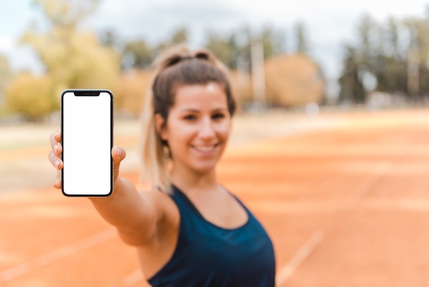 Sportliche Frau, die Smartphoneschablone darstellt