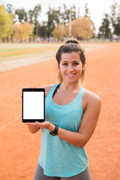 Sportliche Frau, die Tablettenschablone darstellt