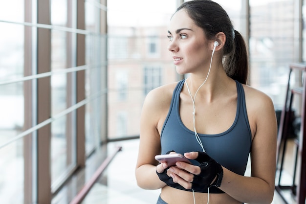 Sportliche Frau mit dem Telefon, das weg schaut