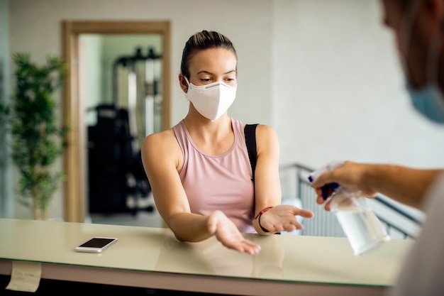 Kostenloses Foto sportliche frau mit gesichtsmaske, die sich im fitnessstudio die hände desinfizieren lässt