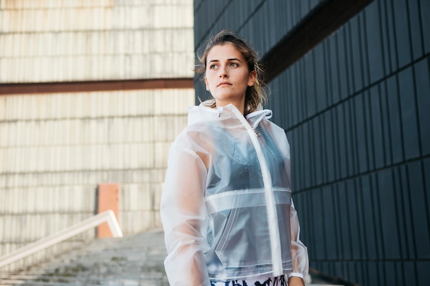 Sportliche Frau mit Regenjacke in der städtischen Umwelt