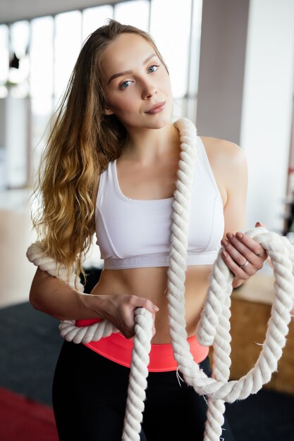 Sportliche junge Frau, die einige Crossfit-Übungen mit einem Seil im Freien macht