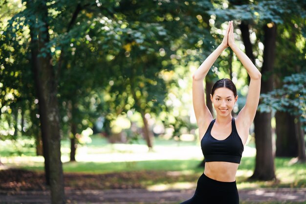 Sportliche junge Frau, die Yoga im Park am Morgen tut