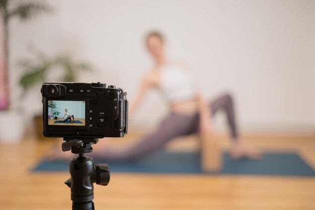 Sportliche junge Frau, die Yoga-Praxis auf weißer Wand mit Pflanzen tut - Konzept des gesunden Lebens und des natürlichen Gleichgewichts zwischen Körper und geistiger Entwicklung