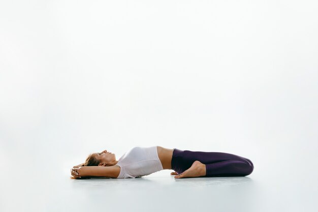 Sportliche junge Frau, die Yoga-Praxis lokalisiert auf weißem Raum tut. Fit flexibles weibliches Modell üben