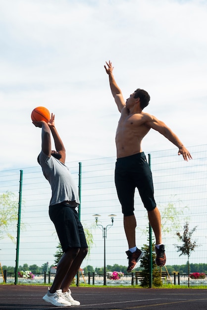 Sportliche Männer, die auf Basketballplatz springen