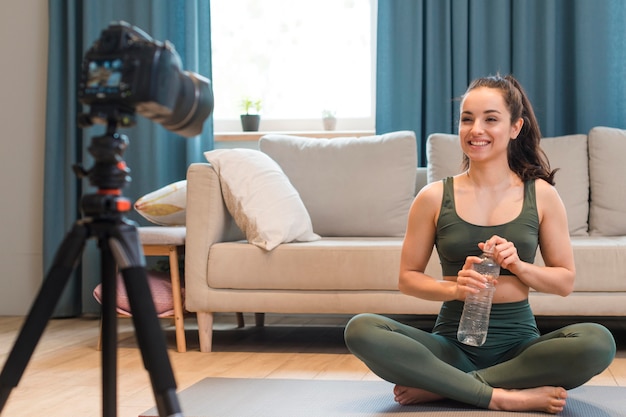 Sportlicher Blogger, der Flasche Wasser sitzt und hält