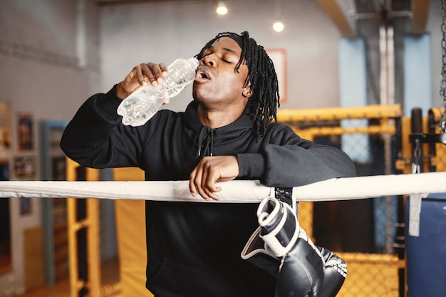 Kostenloses Foto sportlicher mann, der boxt. foto des boxers auf einem ring. afroamerikaner mit flasche wasser.