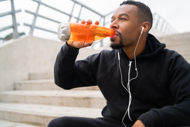 Sportlicher Mann, der etwas nach dem Training trinkt.