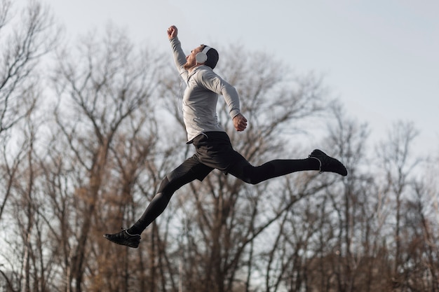 Sportlicher Mann der Seitenansicht, der in Wald springt