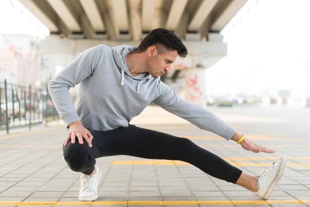 Sportlicher Mann, der sich im Freien ausdehnt