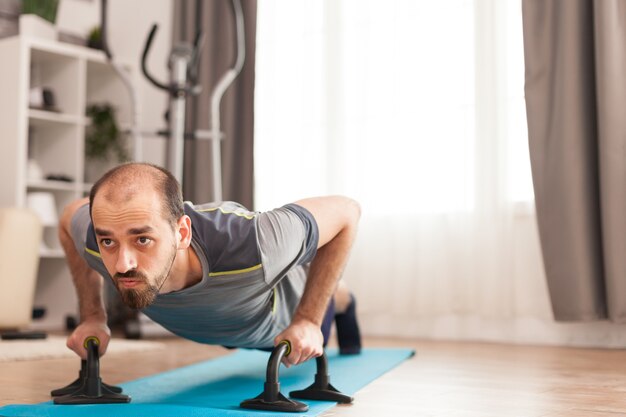Sportlicher Mann, der während der Selbstisolation von Covid-19 Push-Up-Training auf Yogamatte macht.