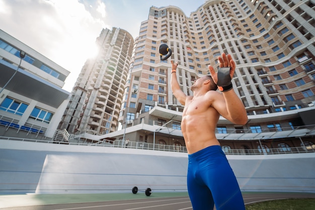 Kostenloses Foto sportliches kerltraining mit kettlebell. foto eines gutaussehenden mannes mit gutem körperbau. kraft und motivation.