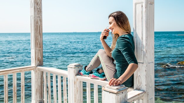 sportliches Mädchen am Pier mit dem Telefon