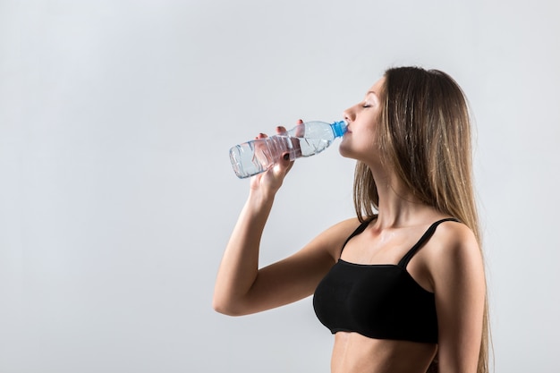 Sportliches Mädchen trinkt Wasser nach Sporttraining