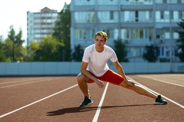 Sportliches Training. Junger kaukasischer sportlicher Mann, männlicher Athlet, Läufer, der allein im öffentlichen Stadion übt