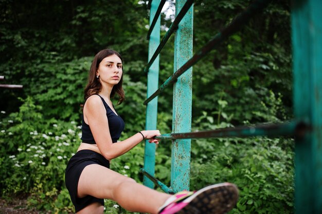 Sportmädchen in der Sportkleidung, die an der horizontalen Stange trainiert, trainiert in einem grünen Park und trainiert in der Natur Ein gesunder Lebensstil