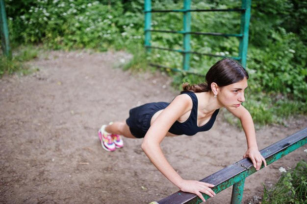 Sportmädchen in der Sportkleidung, die an der horizontalen Stange trainiert, trainiert in einem grünen Park und trainiert in der Natur Ein gesunder Lebensstil