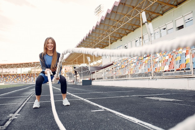 Sportmädchen in einem blauen Uniformtraining am Stadion mit Seil