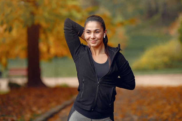 Sportmädchen in einem schwarzen spitzentraining in einem herbstpark