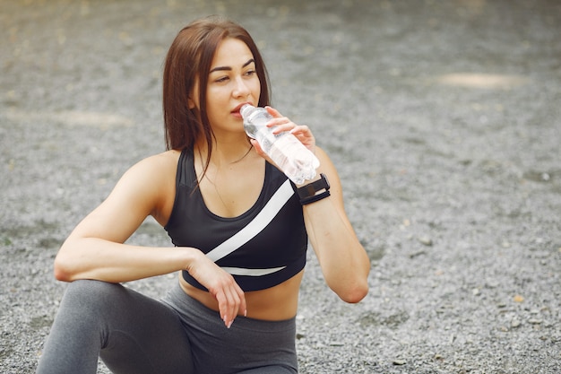 Sportmädchen in Sportkleidung ein Wasser trinkend