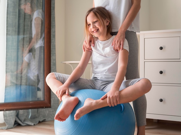 Sportpraxis von Mutter und Mädchen am Ball