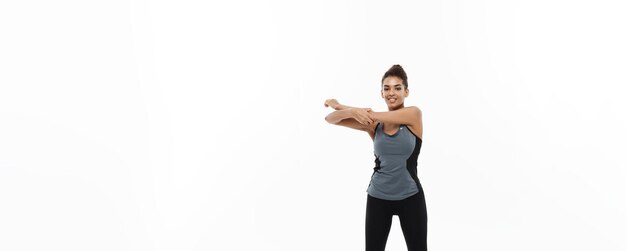 Sporttraining Lifestyle und Fitnesskonzept Ganzkörperporträt einer schönen, glücklichen afroamerikanischen Frau, die sich die Hände isoliert auf weißem Studiohintergrund streckt