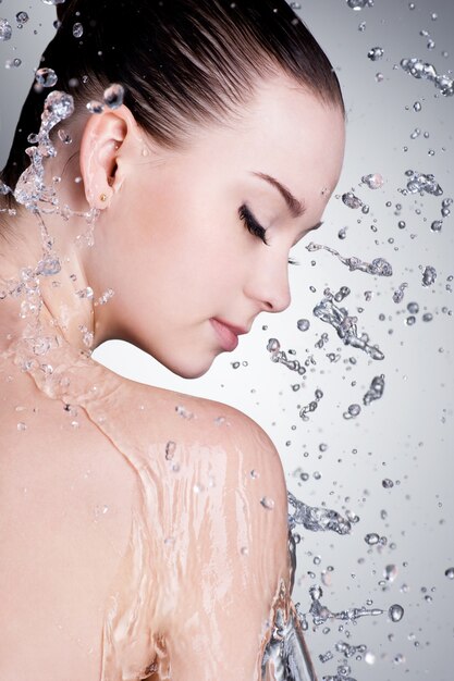 Spritzer und Wassertropfen um das weibliche Gesicht mit sauberer Haut - vertikal