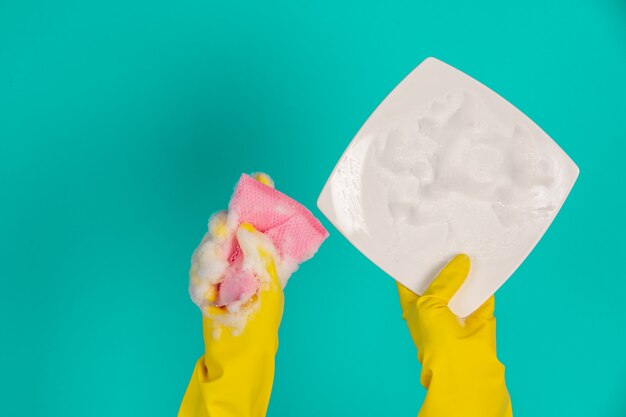 Spülmaschine, die gelbe Handschuhe auf einem Blau trägt.