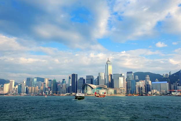 Städtische Architektur in Hong Kong Victoria Harbour am Tag mit blauem Himmel, Boot und Wolken.