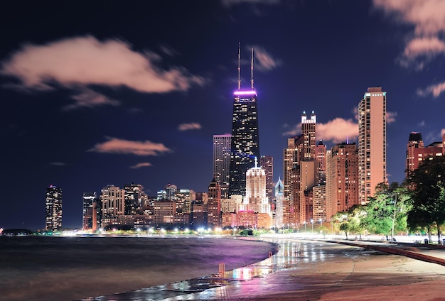 Städtischer Wolkenkratzer der Stadt Chicago bei Nacht am Seeufer in der Innenstadt, beleuchtet mit Lake Michigan und Wasserreflexion vom North Avenue Beach aus gesehen.