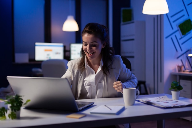 Standpunkt der Geschäftsfrau, die eine Videokonferenz mit dem Team hat, das um Mitternacht im Geschäftsbüro sitzt sitting