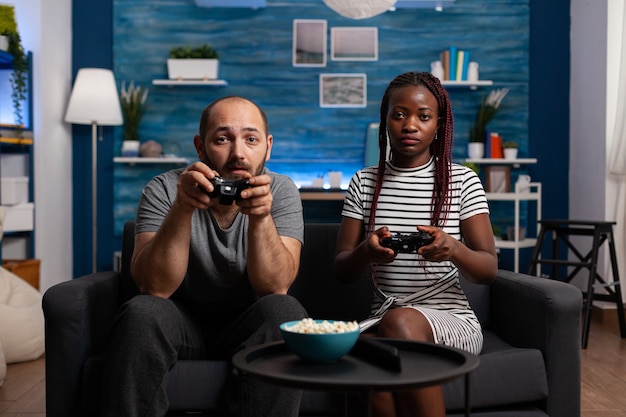 Standpunkt eines interracial Paares, das ein Videospiel auf der Konsole spielt