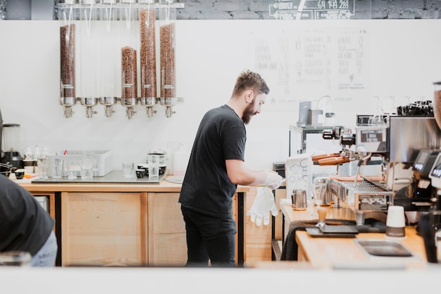 Stangenkonzept mit dem Kellner, der Kaffee macht