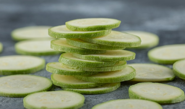 Stapel frische Zucchinischeiben auf grauem Hintergrund, Nahaufnahme Foto.