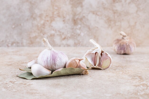 Stapel frischer Bio-Knoblauch auf cremefarbener Oberfläche.