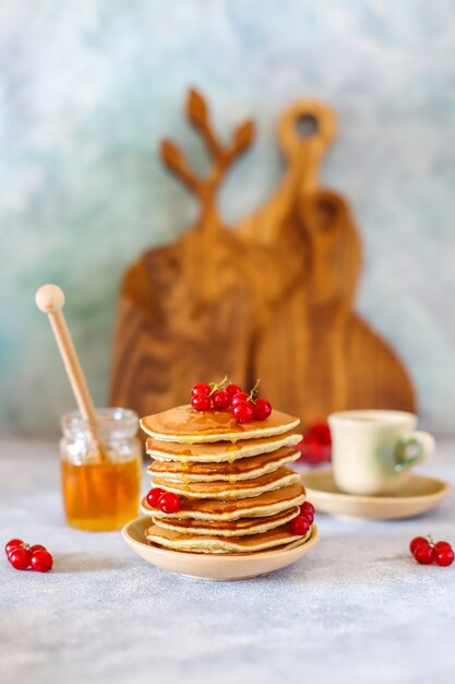 Stapel hausgemachte Pfannkuchen mit Honigsirup und Beeren.