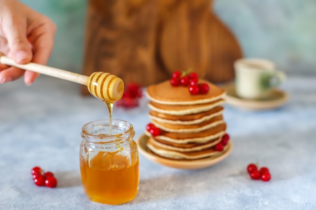 Stapel hausgemachte Pfannkuchen mit Honigsirup und Beeren.