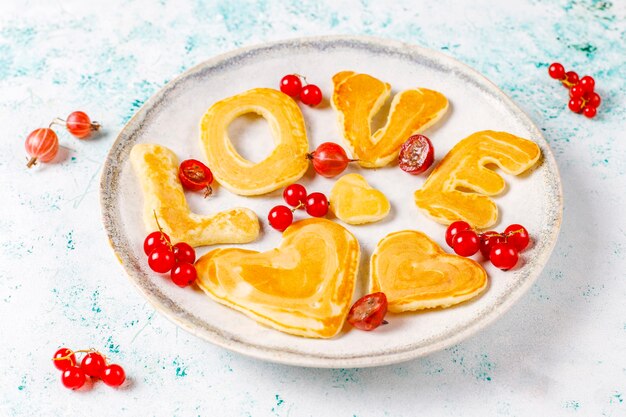 Stapel hausgemachte Pfannkuchen mit Honigsirup und Beeren.