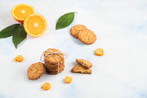 Stapel hausgemachter Kekse mit Orange und Blättern auf weißer Oberfläche.