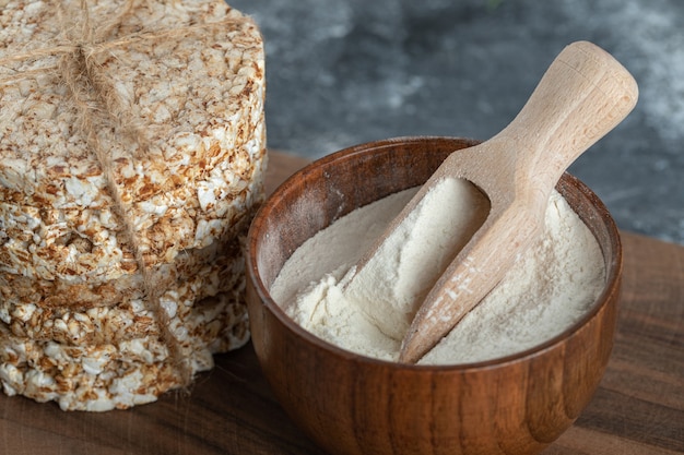 Stapel Reiskuchen und Schüssel Mehl auf Holzbrett